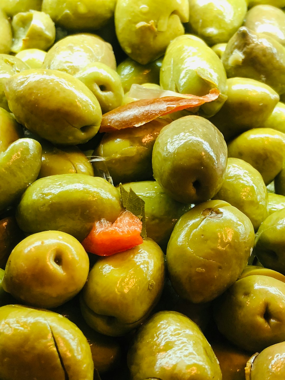 Olives vertes en tas avec poivrons et feuilles de laurier.