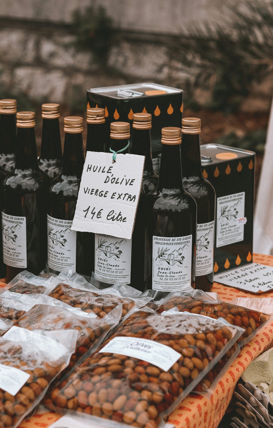 Bouteilles d'huile d'olive et olives en vente sur un étal de marché.